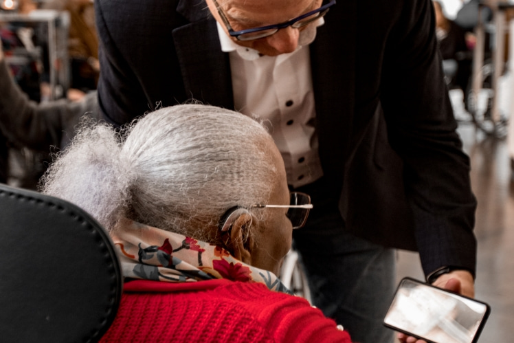Bewoonster van De Makroon kijkt mee op de smart phone van een bezoeker in DeLaMar