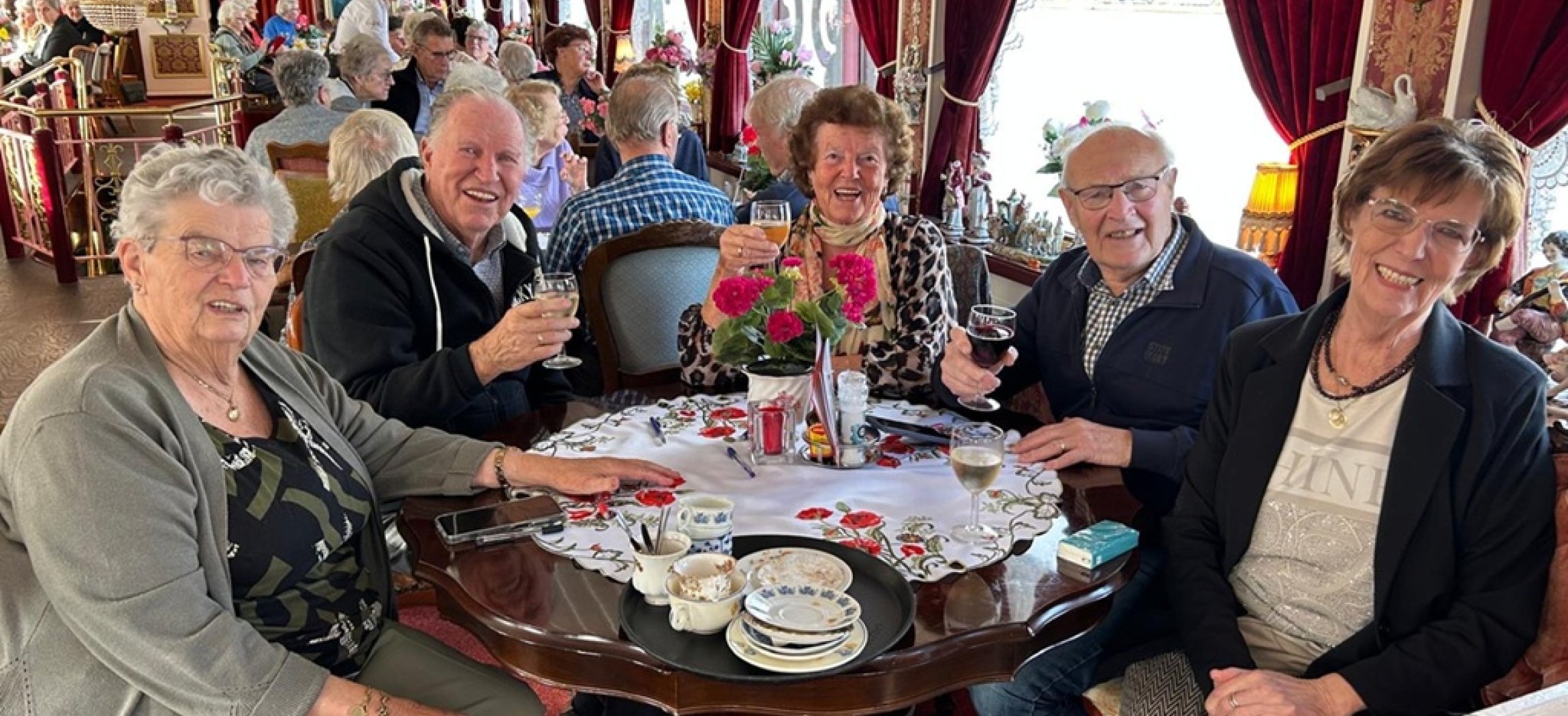 Ouderen drinken koffie aan tafel tijdens boottocht op de Rijn