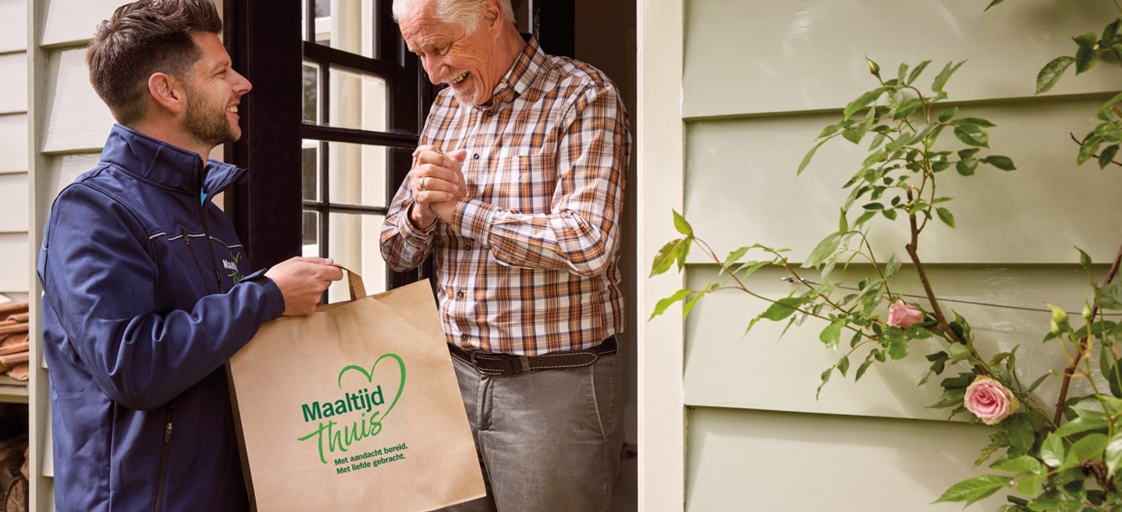 bezorger levert tas  met maaltijd af aan de deur bij oudere man