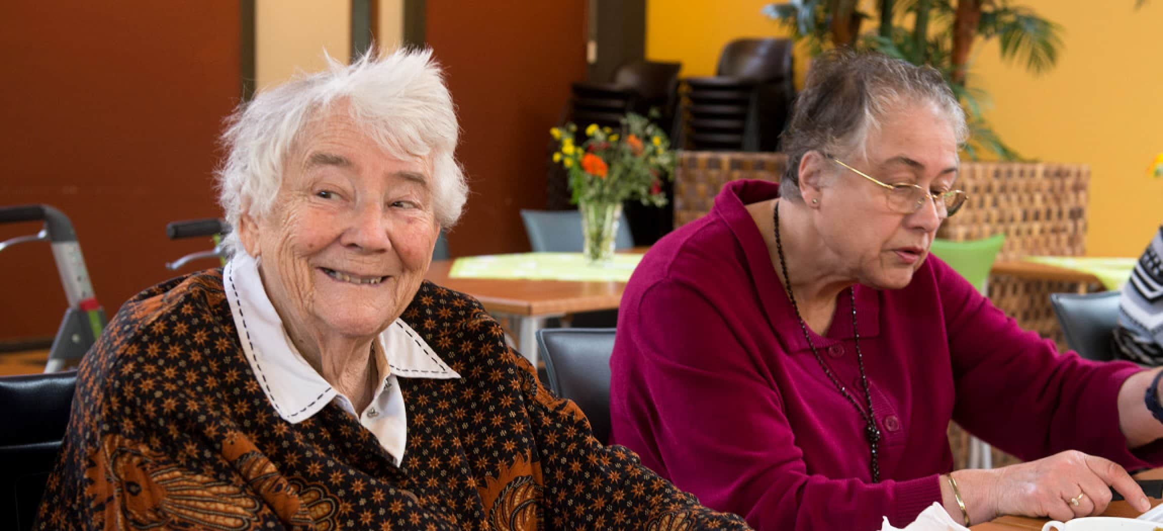 Lieve oude vrouw kijkt vrolijk om zich heen in verpleeghuis