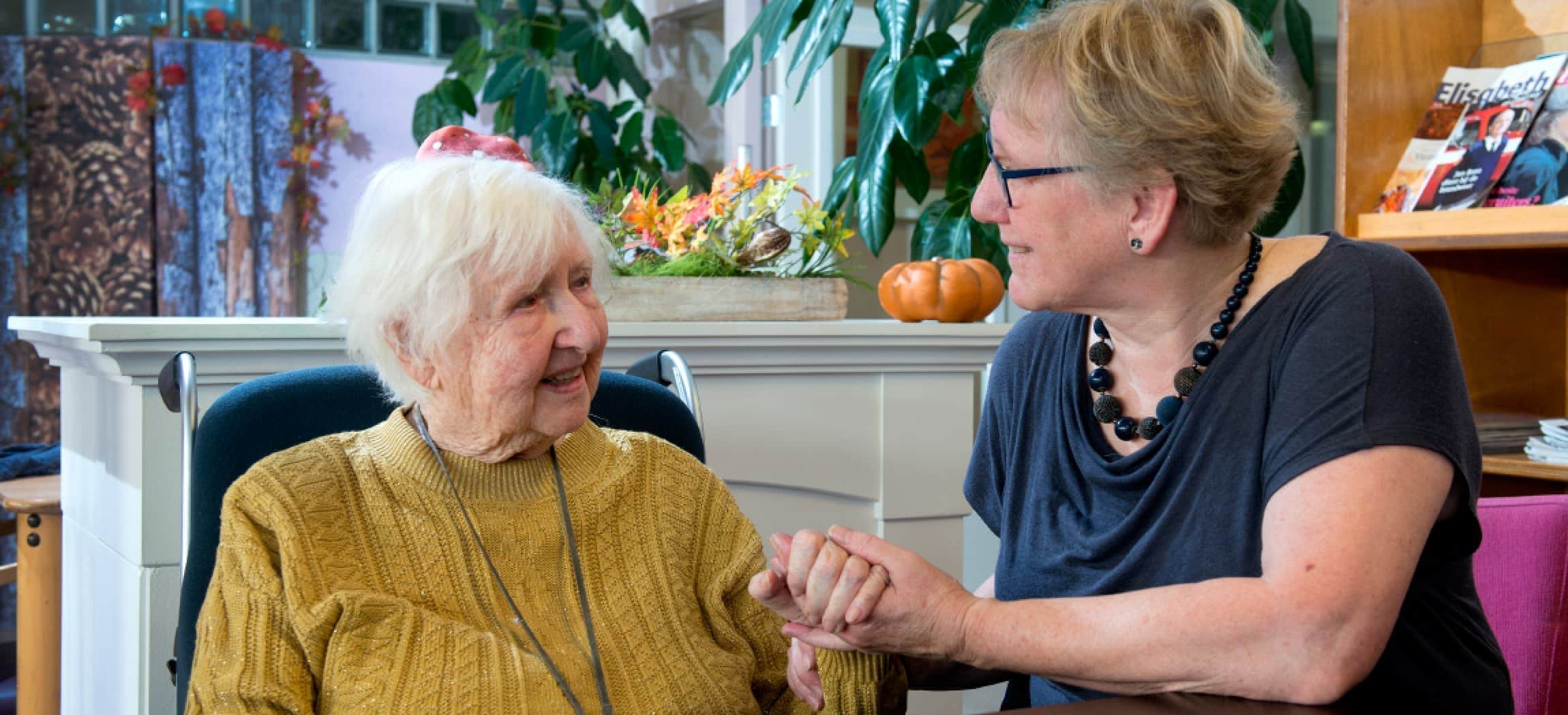 Vrouw houdt hand vast van oude dame