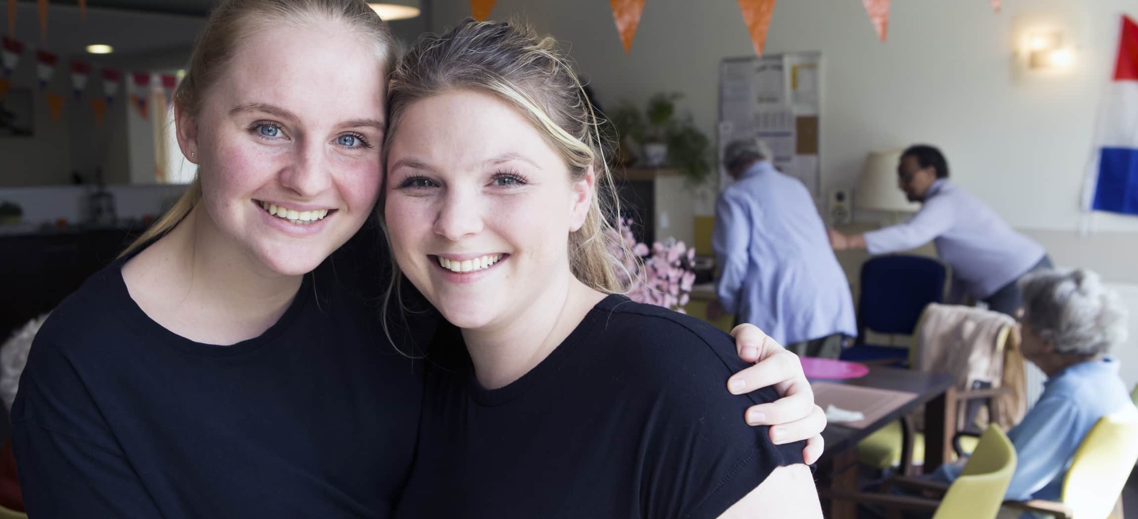 MBO-verpleegkundige en HBO-verpleegkundige met zwarte t-shirts in huiskamer verzorgingshuis