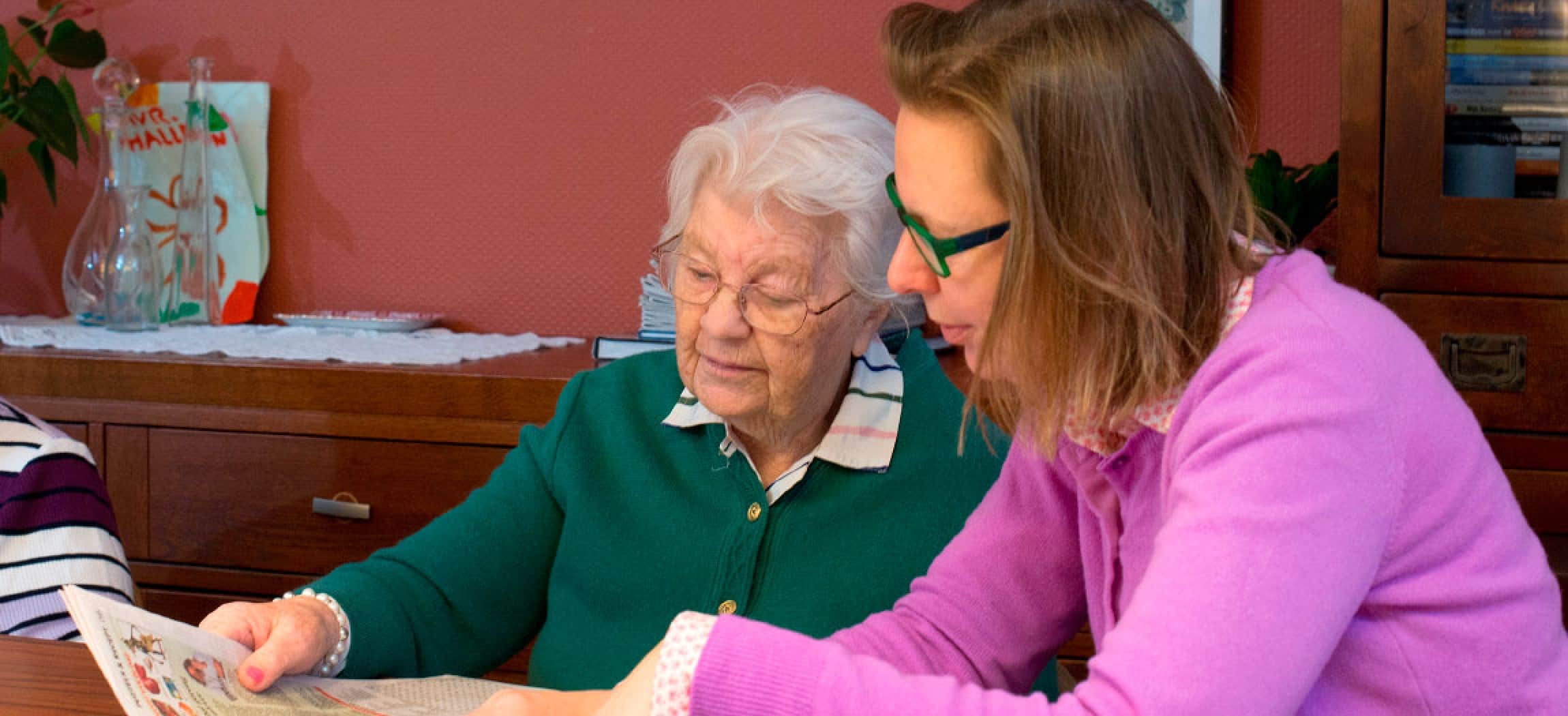 Oudere vrouw en haar dochter lezen samen de krant