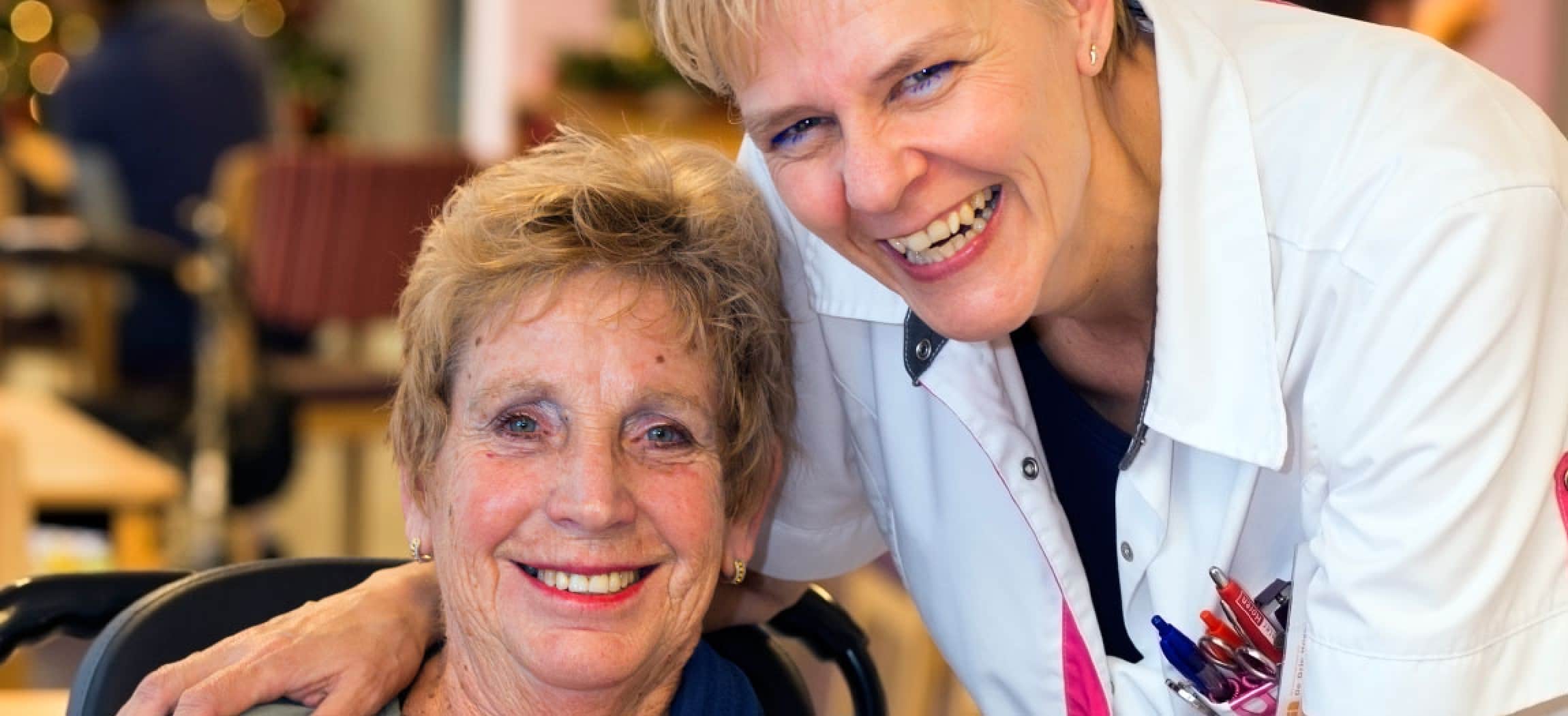 Lachende verpleegkundige omarmt oudere vrouw