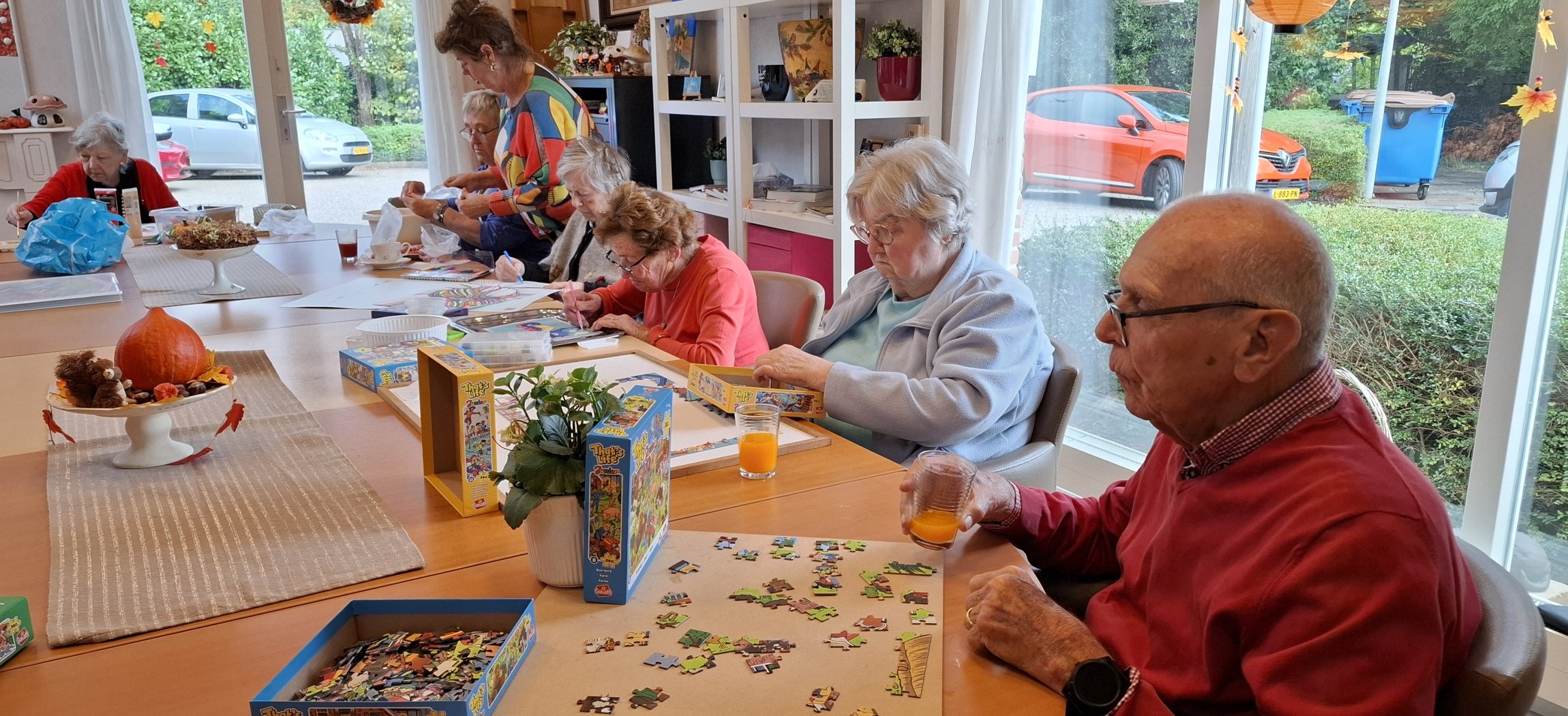 Blije oude vrouw met wit haar verzorgt samen de geraniums buiten op terras