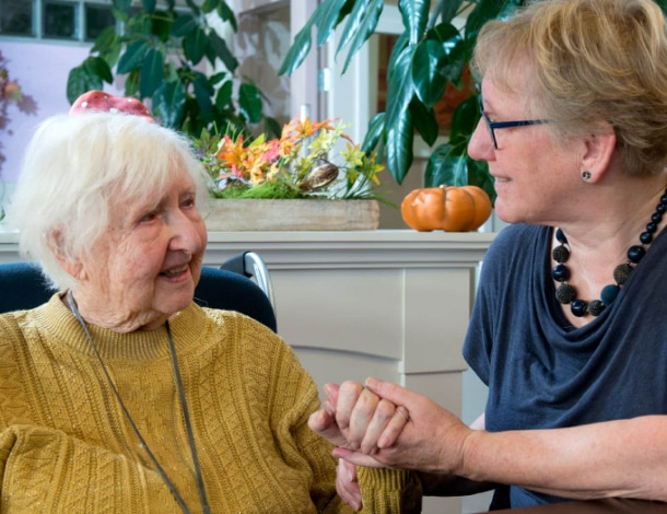 Vrouw houdt hand vast van oude dame